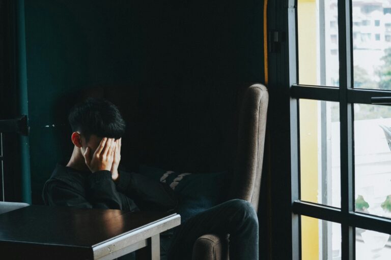 a person sitting in an office with their hands over their face